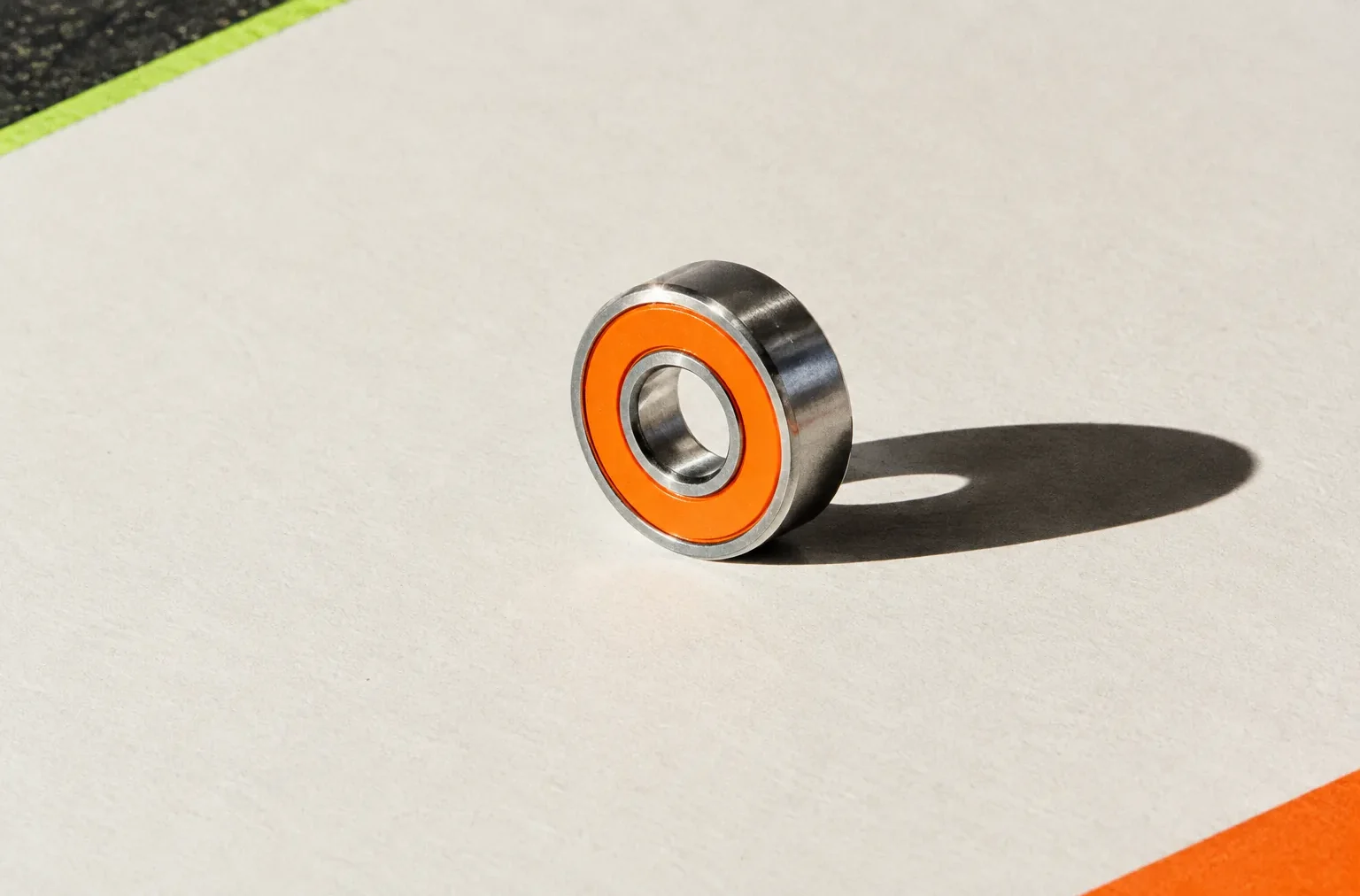 A single chrome skate bearing resting on heavy chalk-white paper