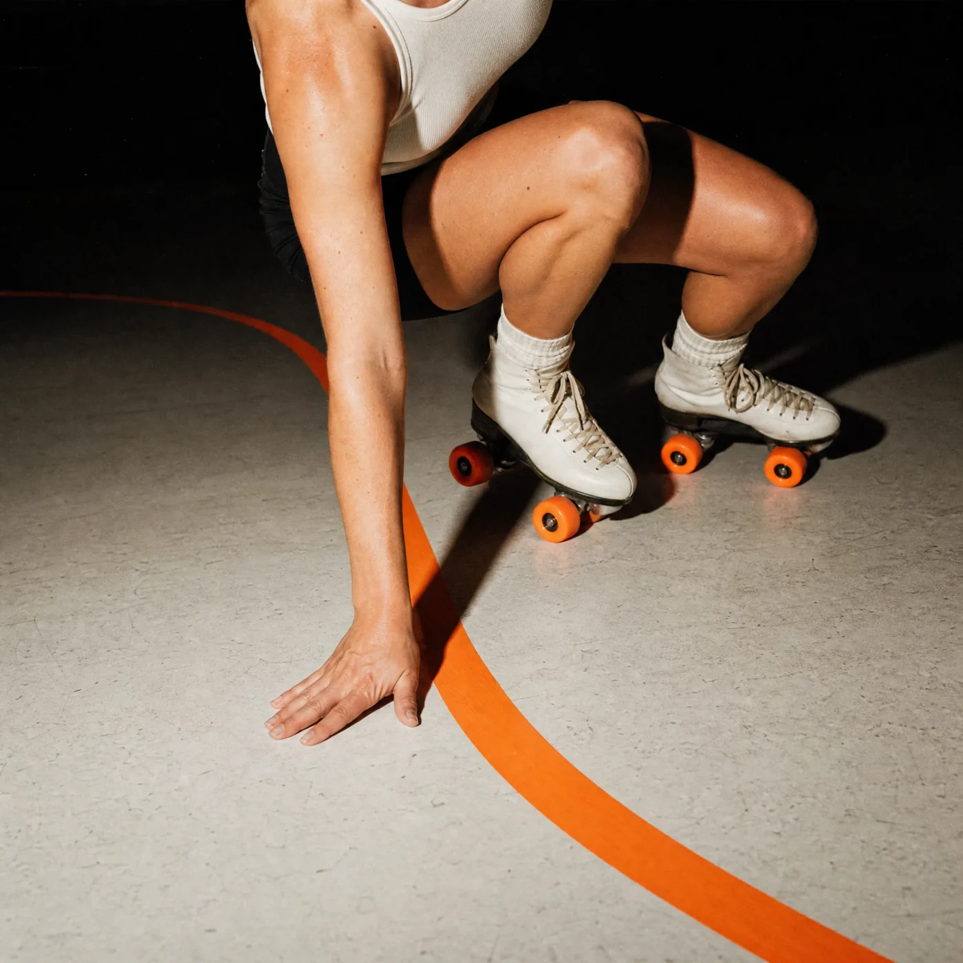 Overhead shot of a skater crouching to touch the orange track tape line