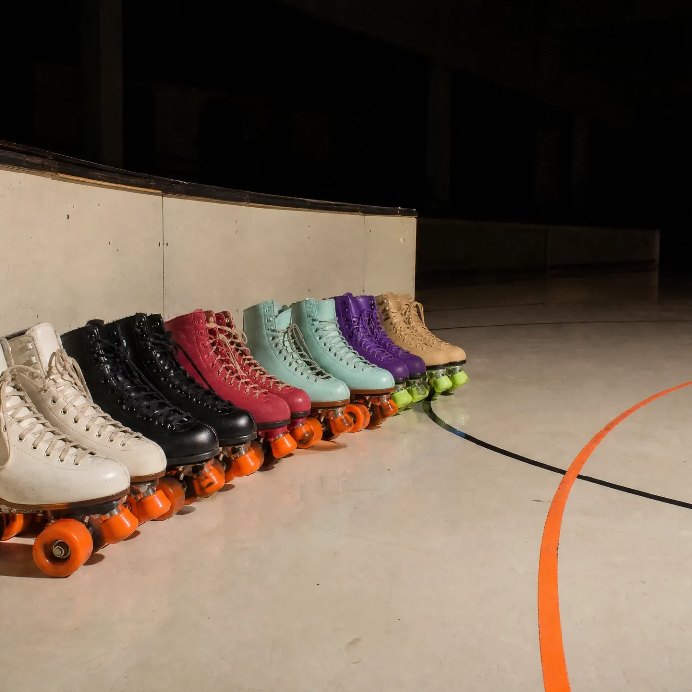 A row of quad skates lined up along the rink wall