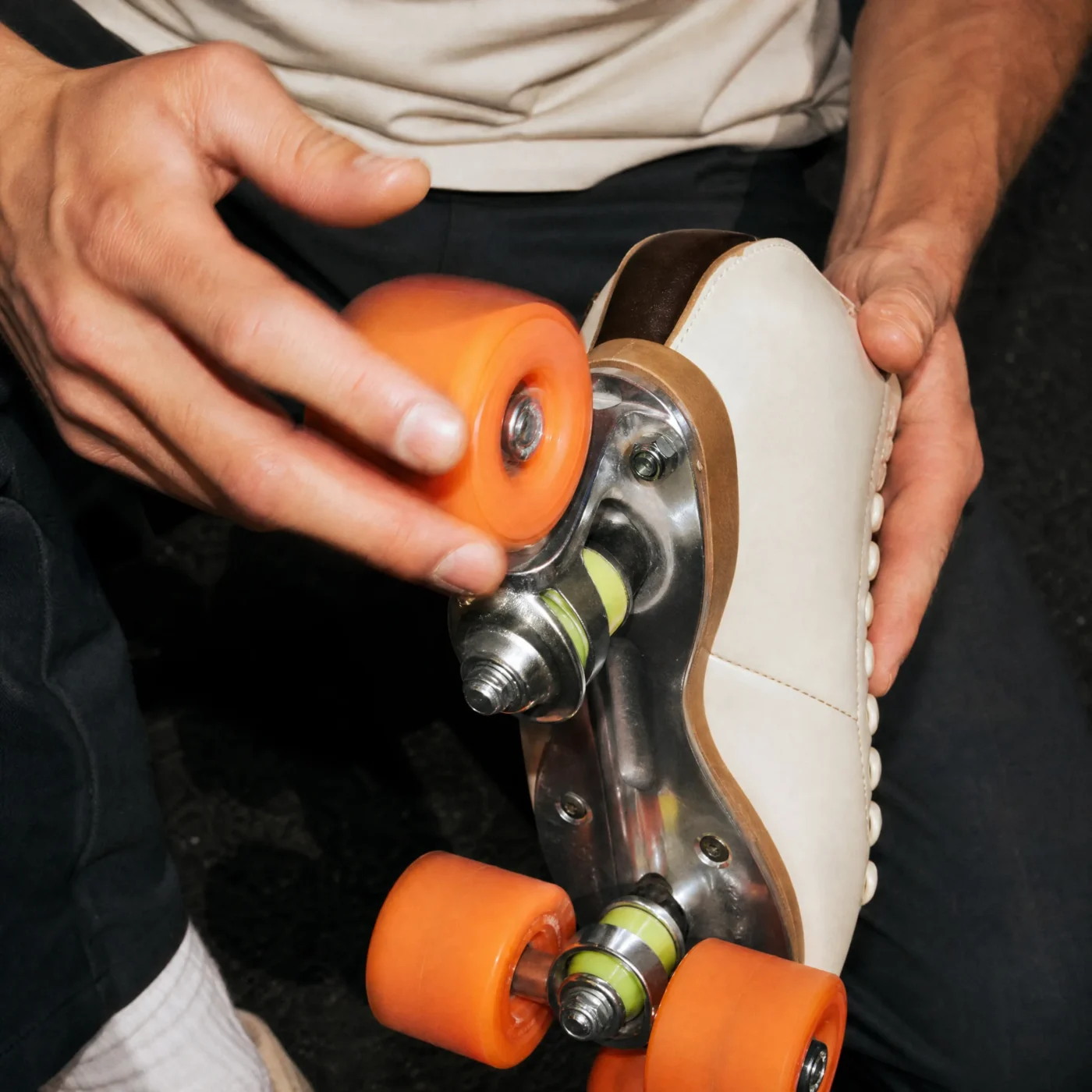Hands spinning an orange wheel on an upturned skate to check the bearings
