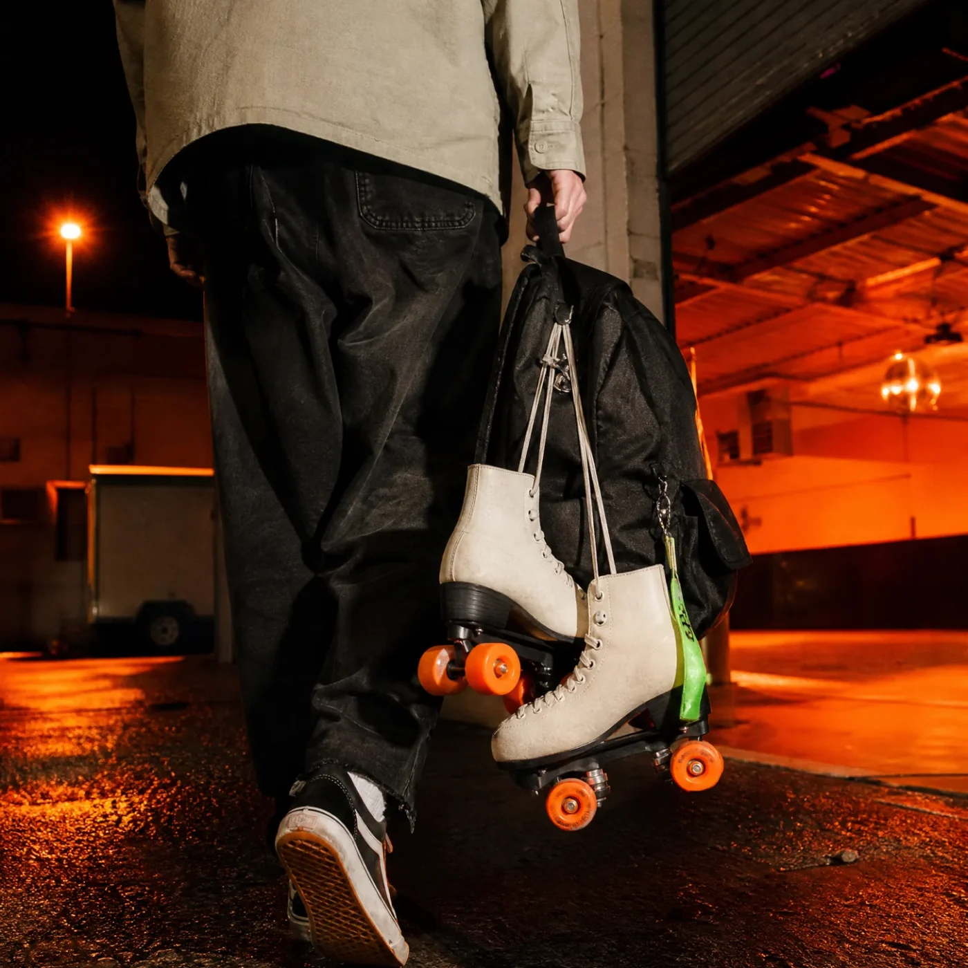 Skater leaving a roller rink at night carrying a backpack with skates attached